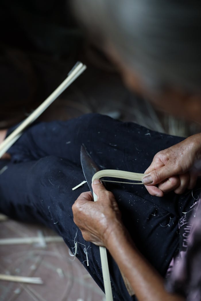 Home A close-up of an elderly person weaving using natural fibers, showcasing traditional craftsmanship.