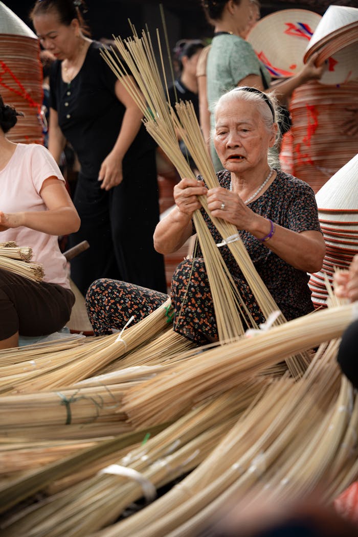 Elderly woman crafting conical hats in Hà Nội, showcasing tradition and culture.